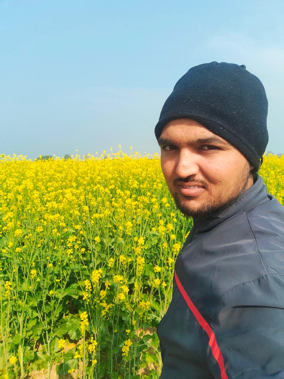 Mohd Mehdi standing in a mustard field at MM Farms